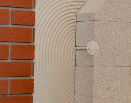 Fixer un isolant sur un mur extérieur avec des chevilles et rondelles pour isolation